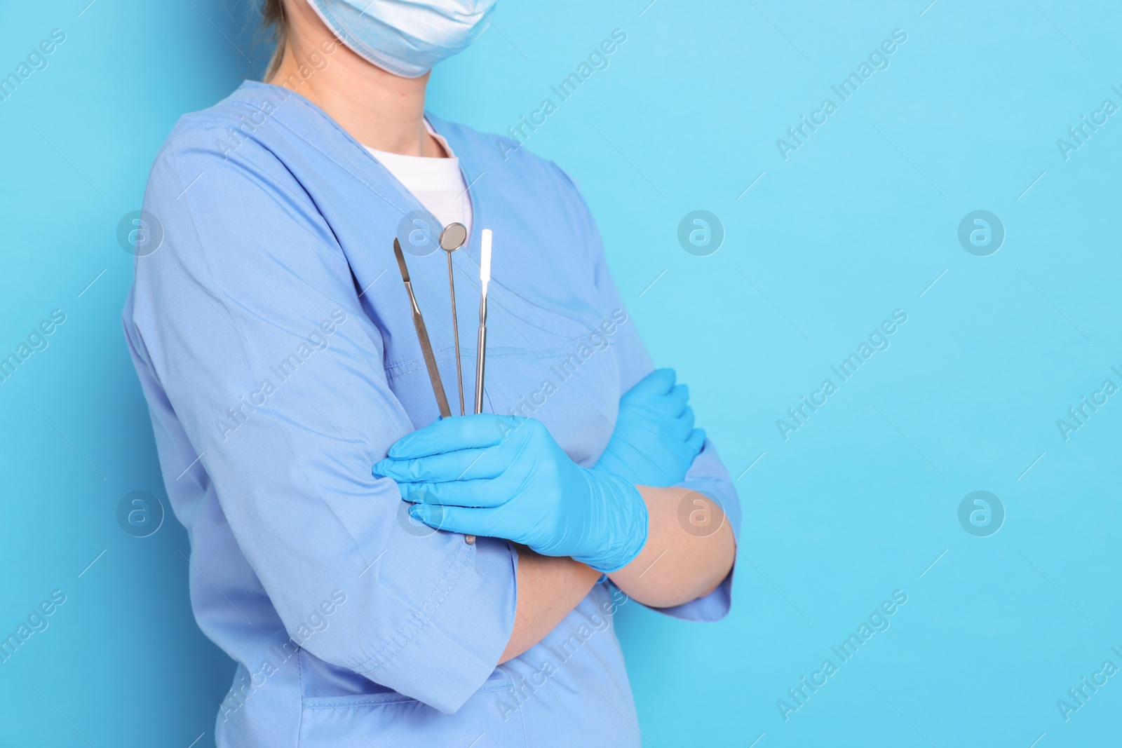 Photo of Professional dentist with tools on light blue background, closeup. Space for text