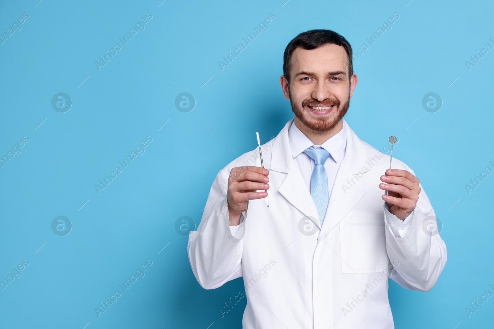 Photo of Professional dentist with tools on light blue background. Space for text