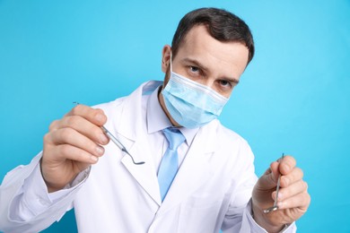 Professional dentist with tools on light blue background