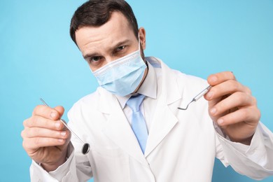 Professional dentist with tools on light blue background