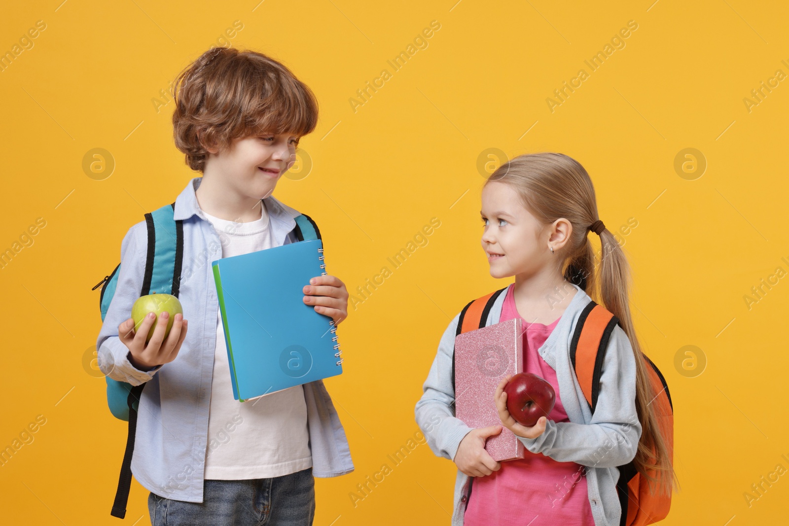 Photo of School children with books and apples on orange background