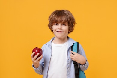 Photo of Little boy with apple on orange background