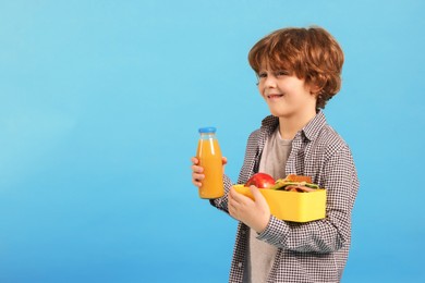 Photo of Cute little boy with lunch box and drink on light blue background. Space for text