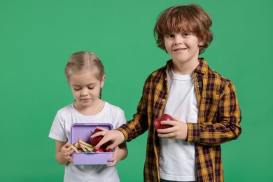 Photo of Cute little children with lunch on green background