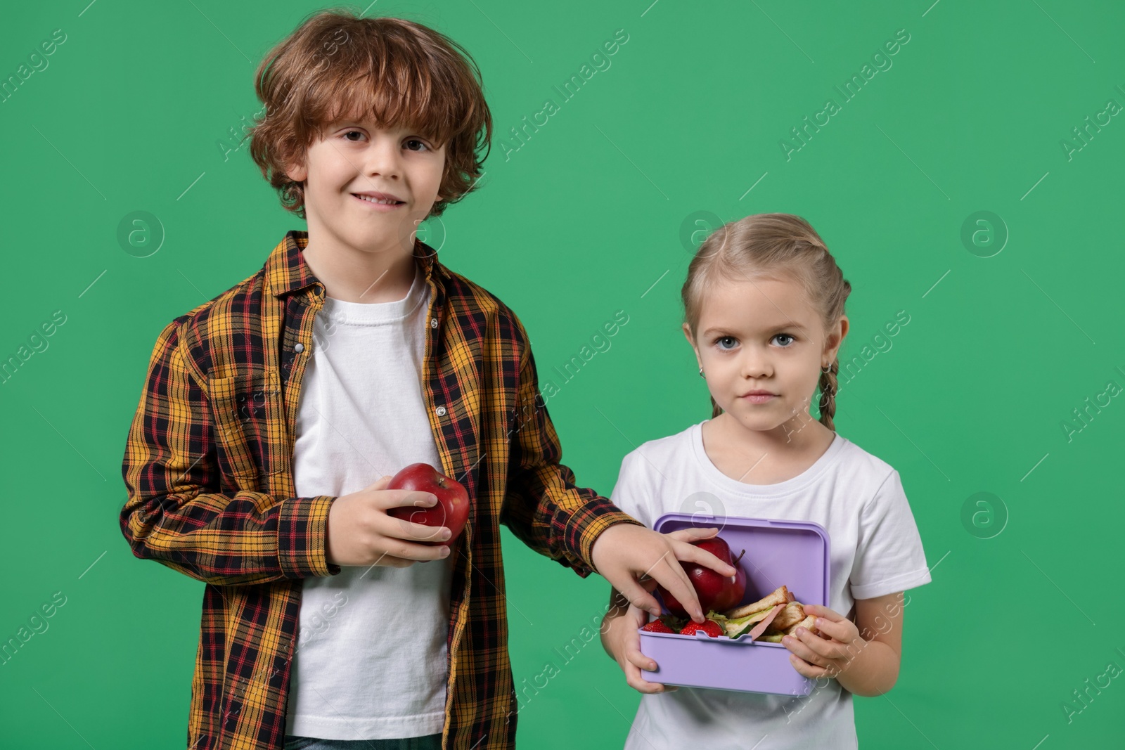 Photo of Cute little children with lunch on green background