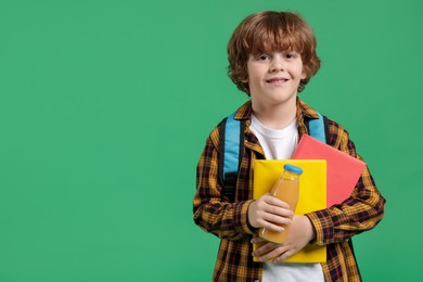 Cute little boy with books and drink on green background. Space for text