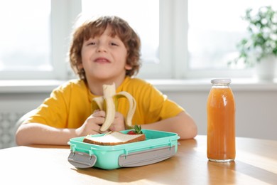 Cute little boy eating lunch at wooden table in school, selective focus