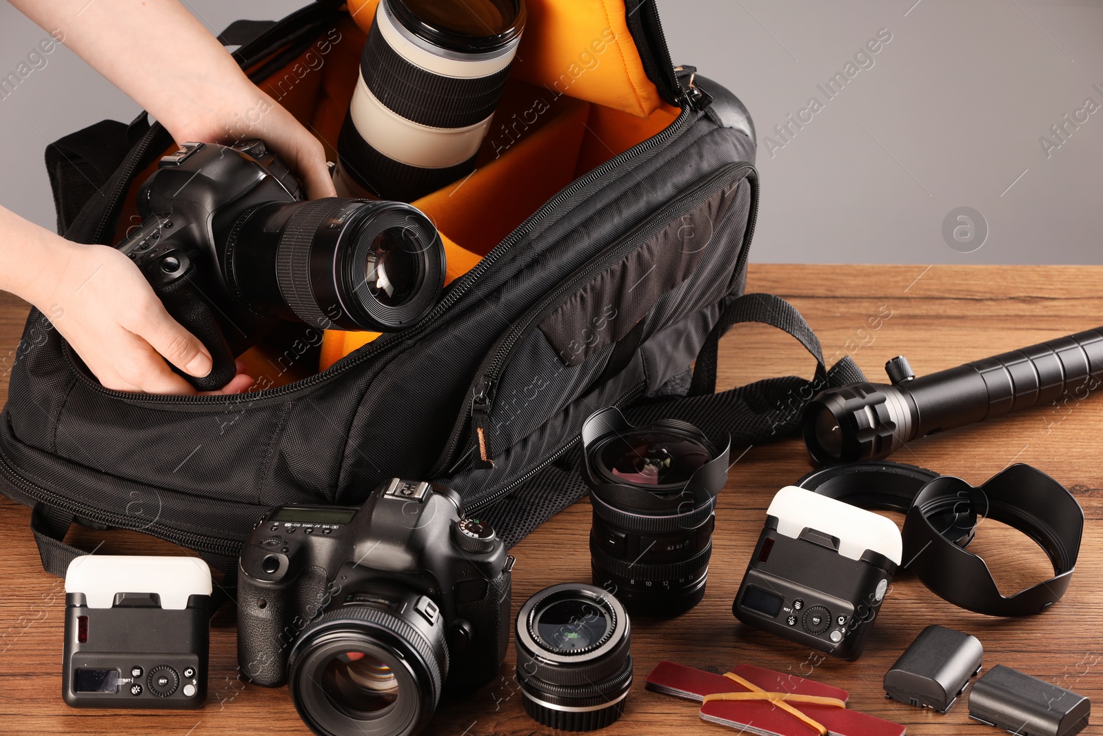 Photographer with professional equipment and backpack at wooden table, closeup Photo of Photographer with professional equipment and backpack at wooden table, closeup