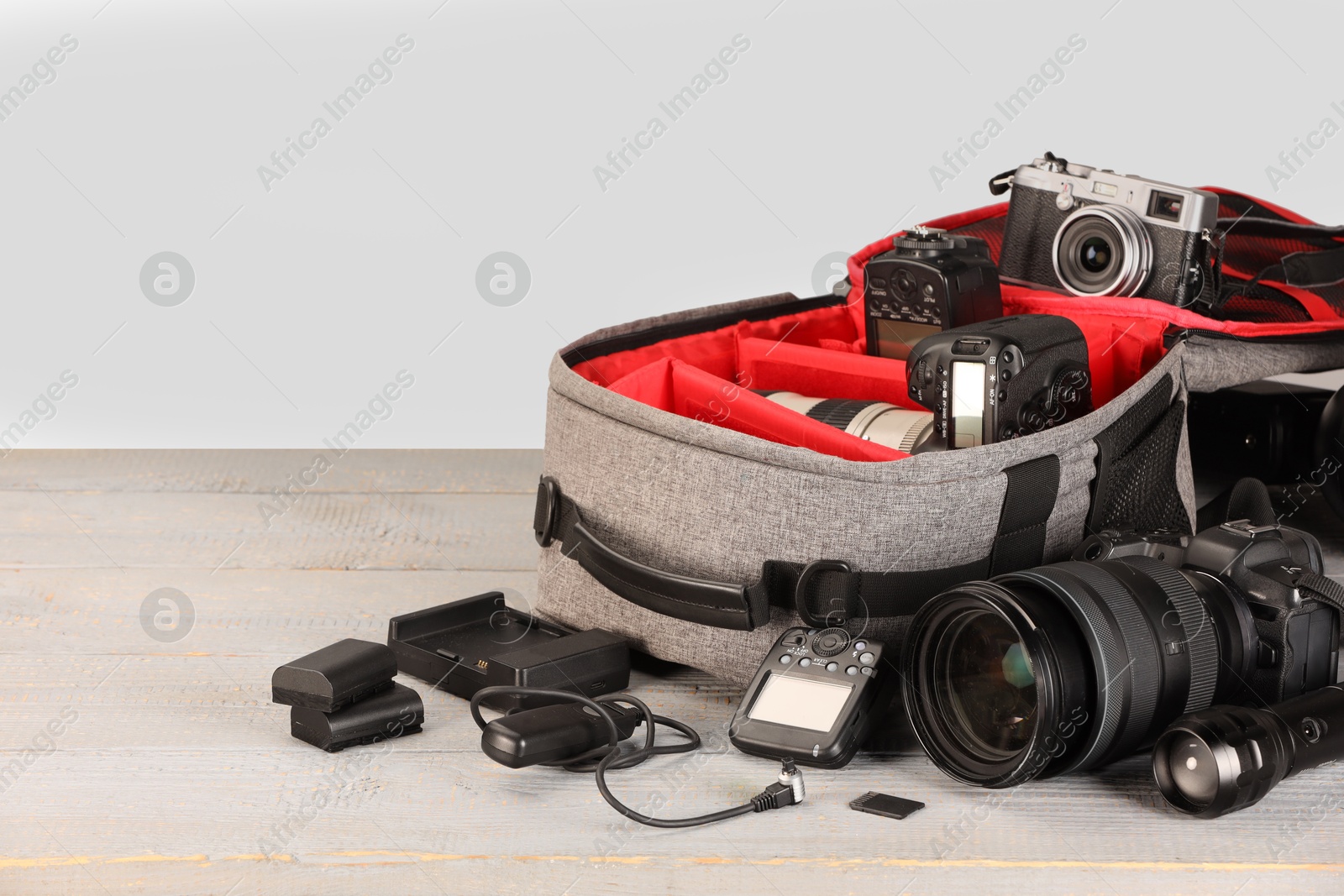 Professional photographer's equipment and backpack on light wooden table. Space for text Photo of Professional photographer's equipment and backpack on light wooden table. Space for text