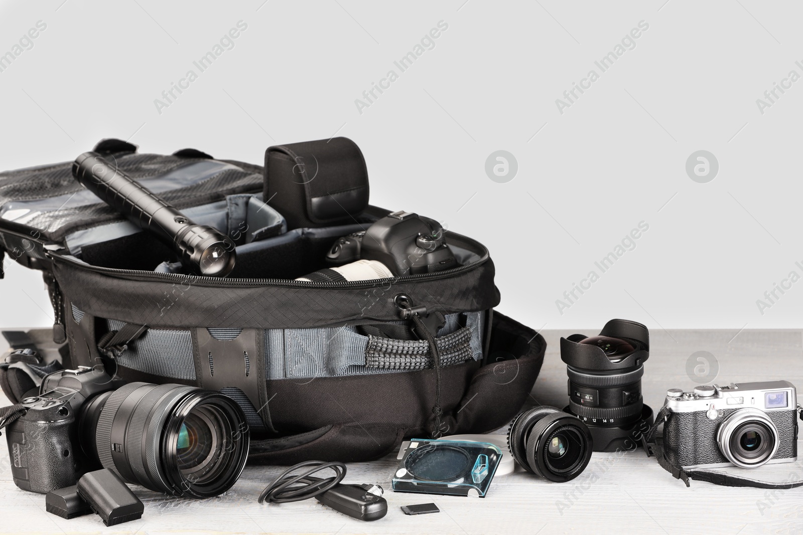 Professional photographer's equipment and backpack on light wooden table. Space for text Photo of Professional photographer's equipment and backpack on light wooden table. Space for text