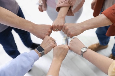 Photo of Unity concept. People holding fists together indoors, above view