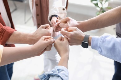 Photo of Unity concept. People holding fists together indoors, closeup