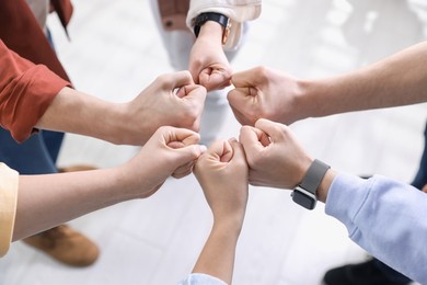 Photo of Unity concept. People holding fists together indoors, closeup