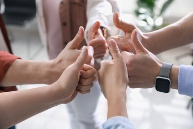 Unity concept. People showing thumbs up indoors, closeup