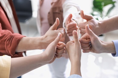 Unity concept. People showing thumbs up indoors, closeup