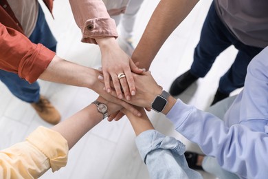 Photo of Unity concept. People holding hands together indoors, closeup