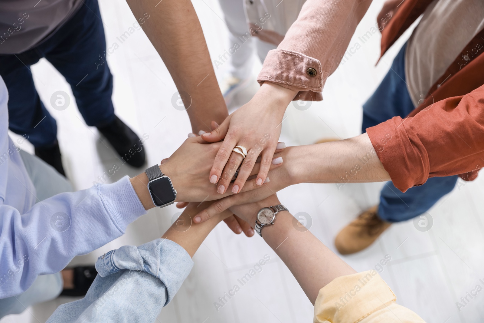 Photo of Unity concept. People holding hands together indoors, closeup