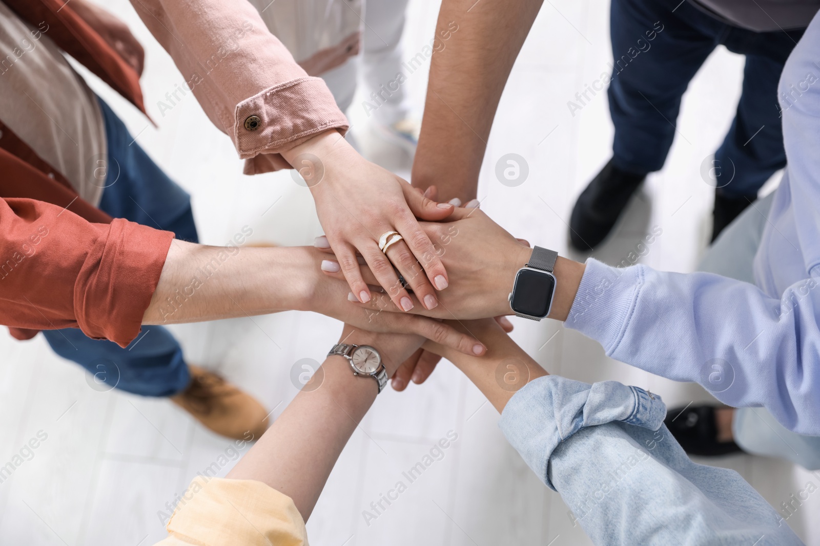 Photo of Unity concept. People holding hands together indoors, closeup