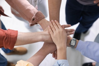 Photo of Unity concept. People holding hands together indoors, above view