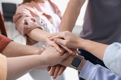 Photo of Unity concept. People holding hands together indoors, closeup