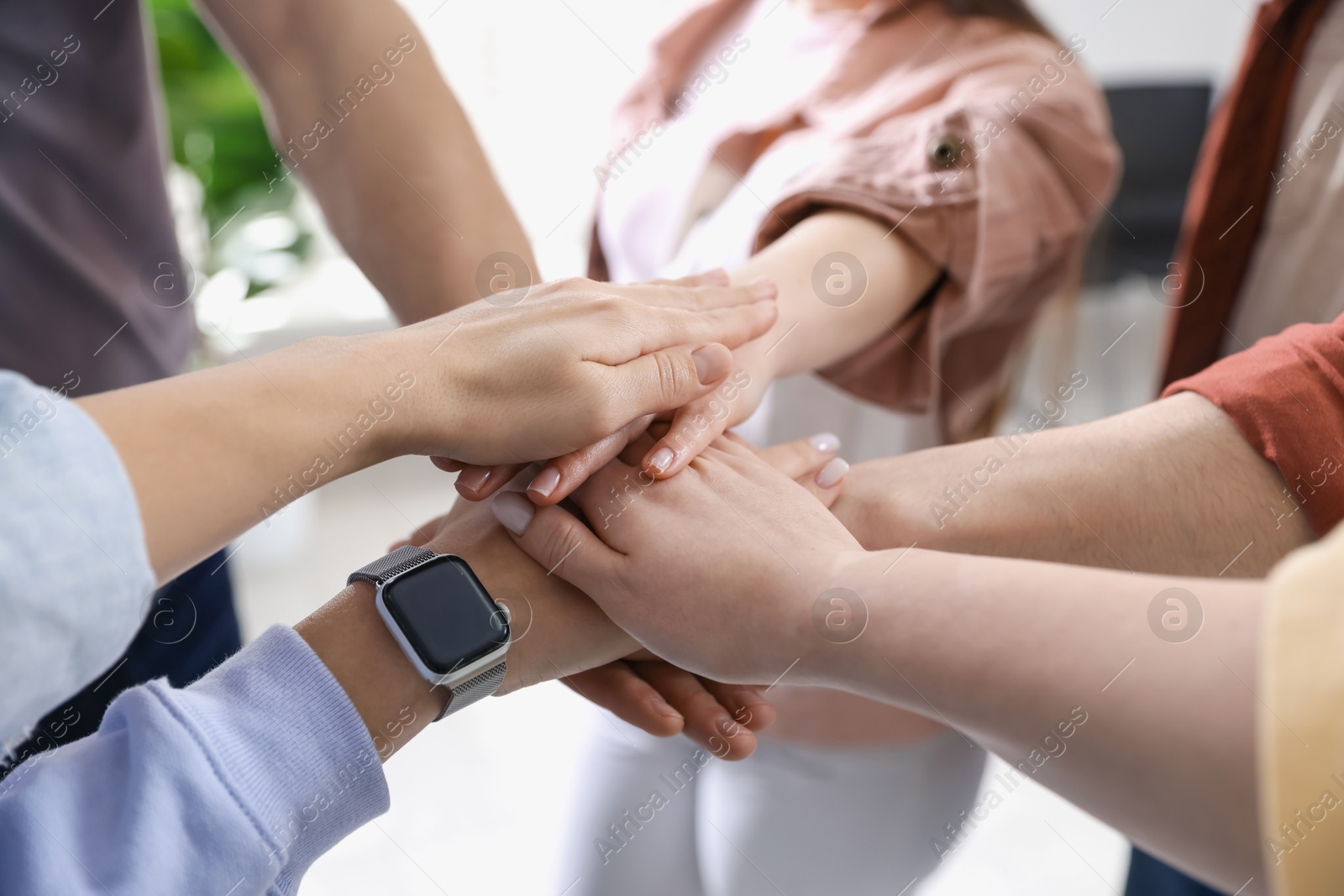 Photo of Unity concept. People holding hands together indoors, closeup