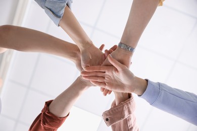 Photo of Unity concept. People holding hands together indoors, bottom view