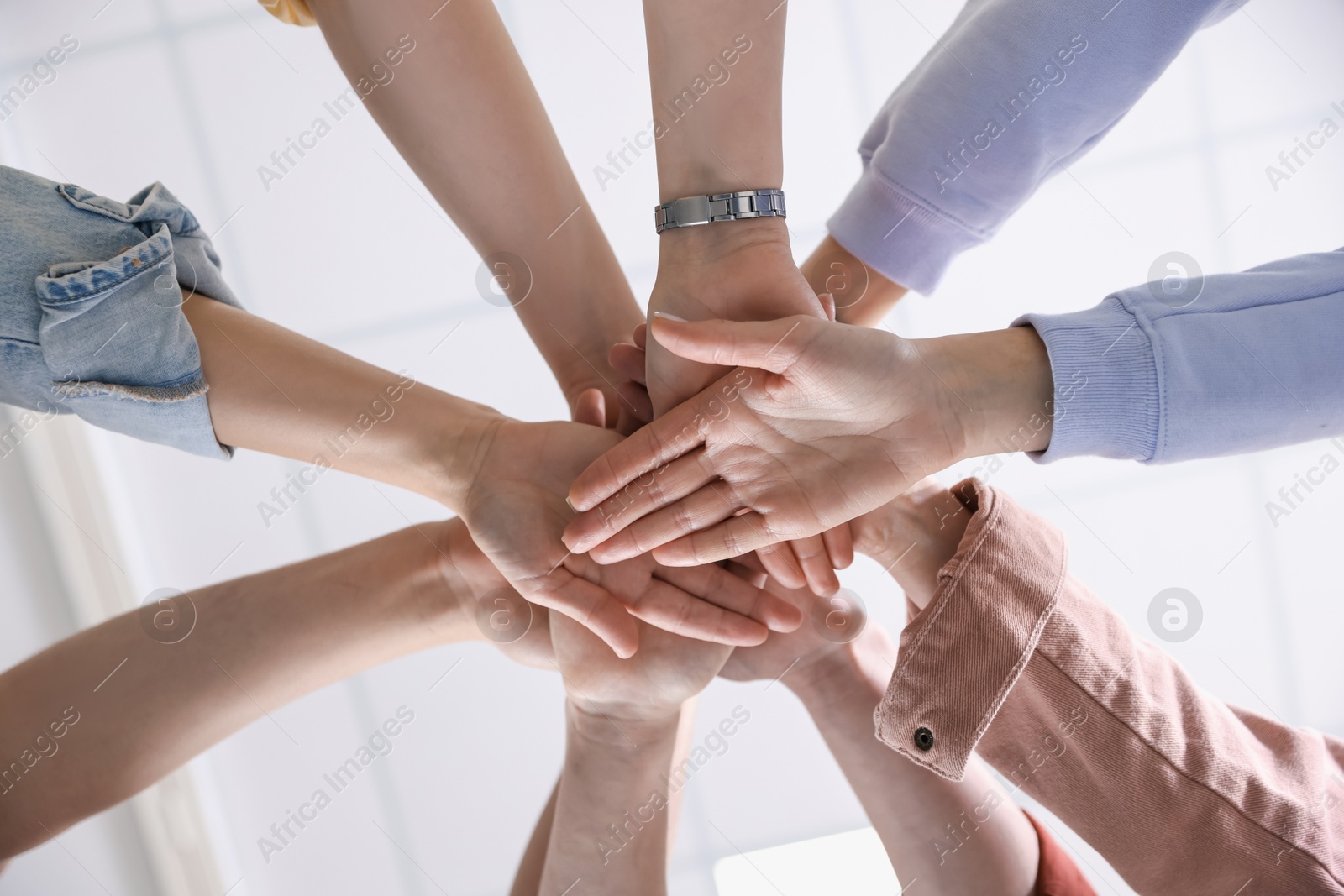 Photo of Unity concept. People holding hands together indoors, bottom view