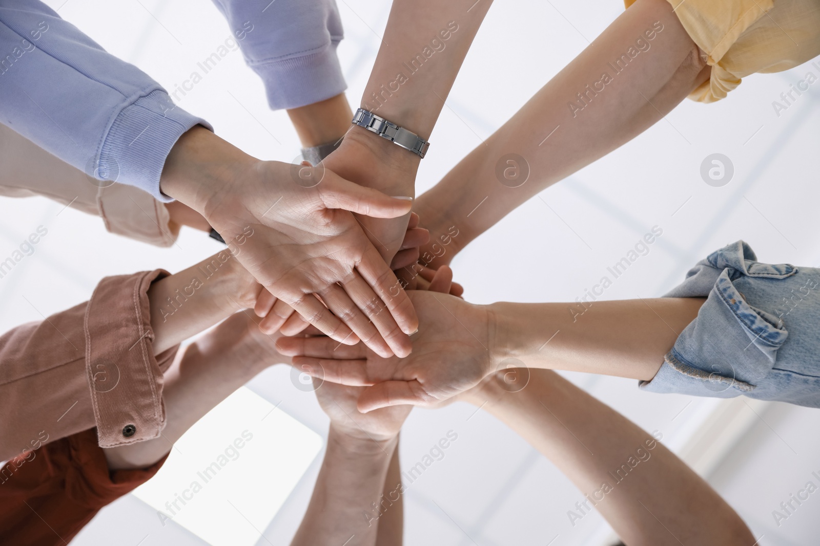 Photo of Unity concept. People holding hands together indoors, bottom view