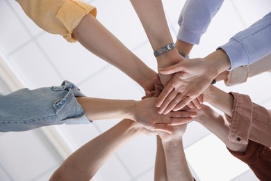 Unity concept. People holding hands together indoors, bottom view