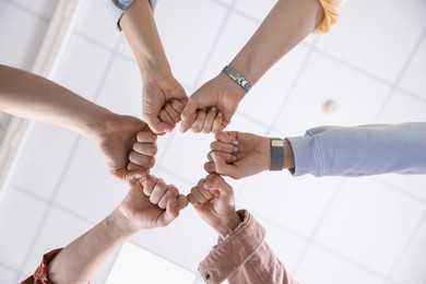 Photo of Unity concept. People holding fists together indoors, bottom view