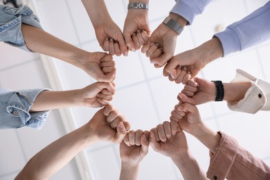 Photo of Unity concept. People holding fists together indoors, bottom view