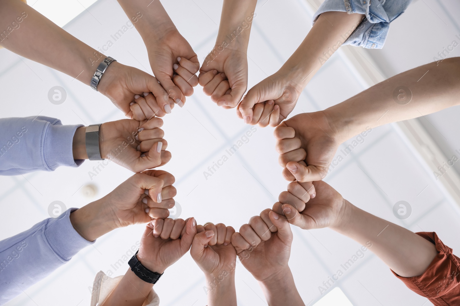 Photo of Unity concept. People holding fists together indoors, bottom view