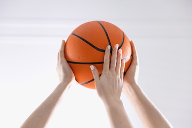 Unity concept. People holding basketball ball together indoors, closeup