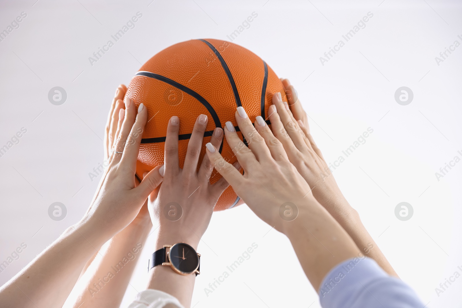 Photo of Unity concept. People holding basketball ball together indoors, closeup