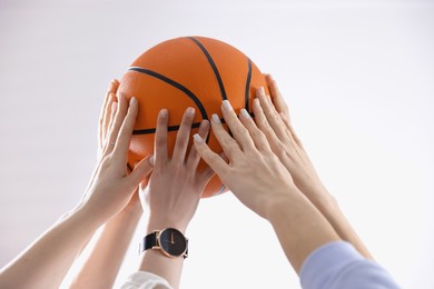 Unity concept. People holding basketball ball together indoors, closeup