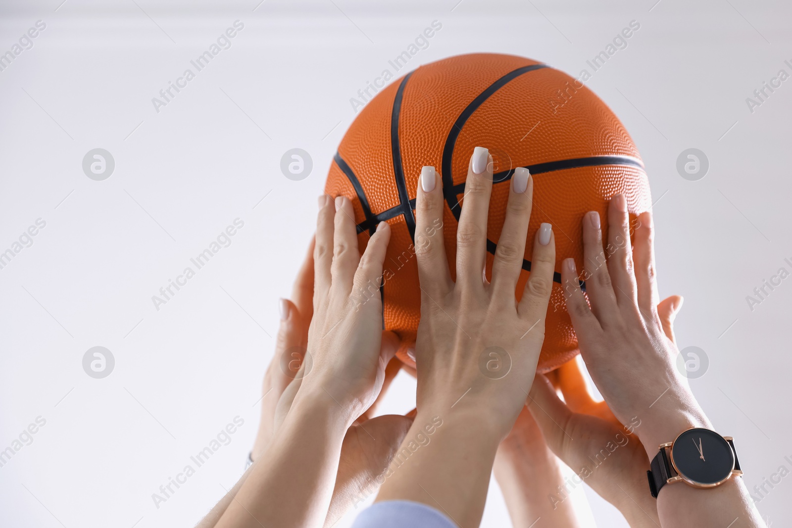 Photo of Unity concept. People holding basketball ball together indoors, closeup