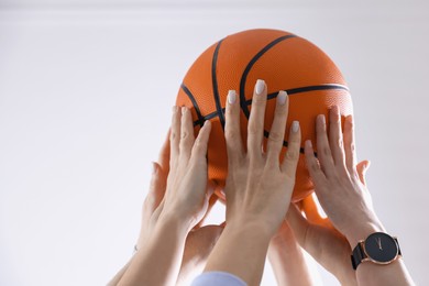 Unity concept. People holding basketball ball together indoors, closeup