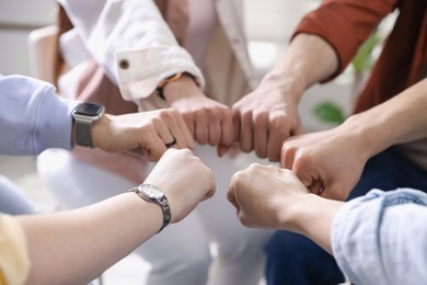 Photo of Unity concept. People holding fists together indoors, closeup