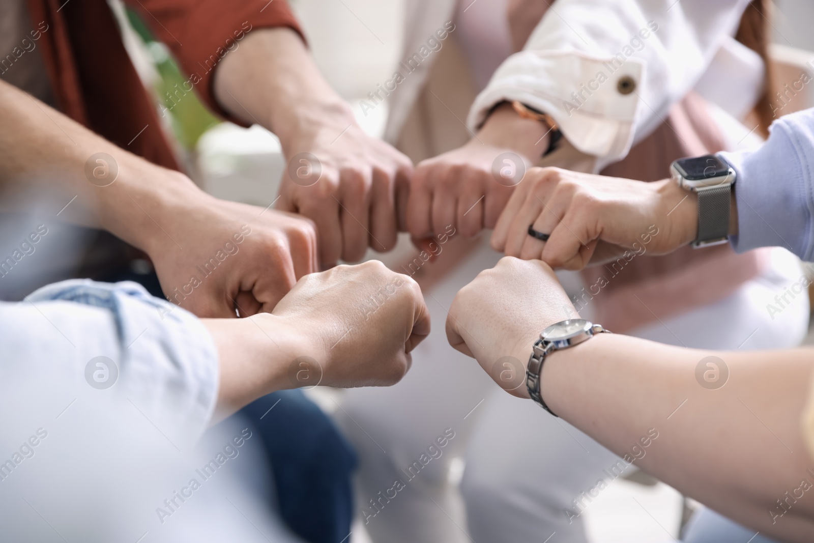 Photo of Unity concept. People holding fists together indoors, closeup