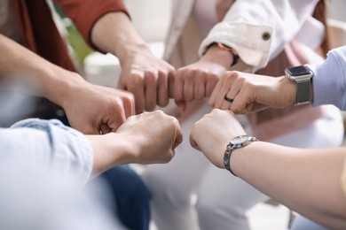 Unity concept. People holding fists together indoors, closeup