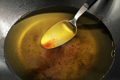 Photo of Used cooking oil and spoon in frying pan, closeup