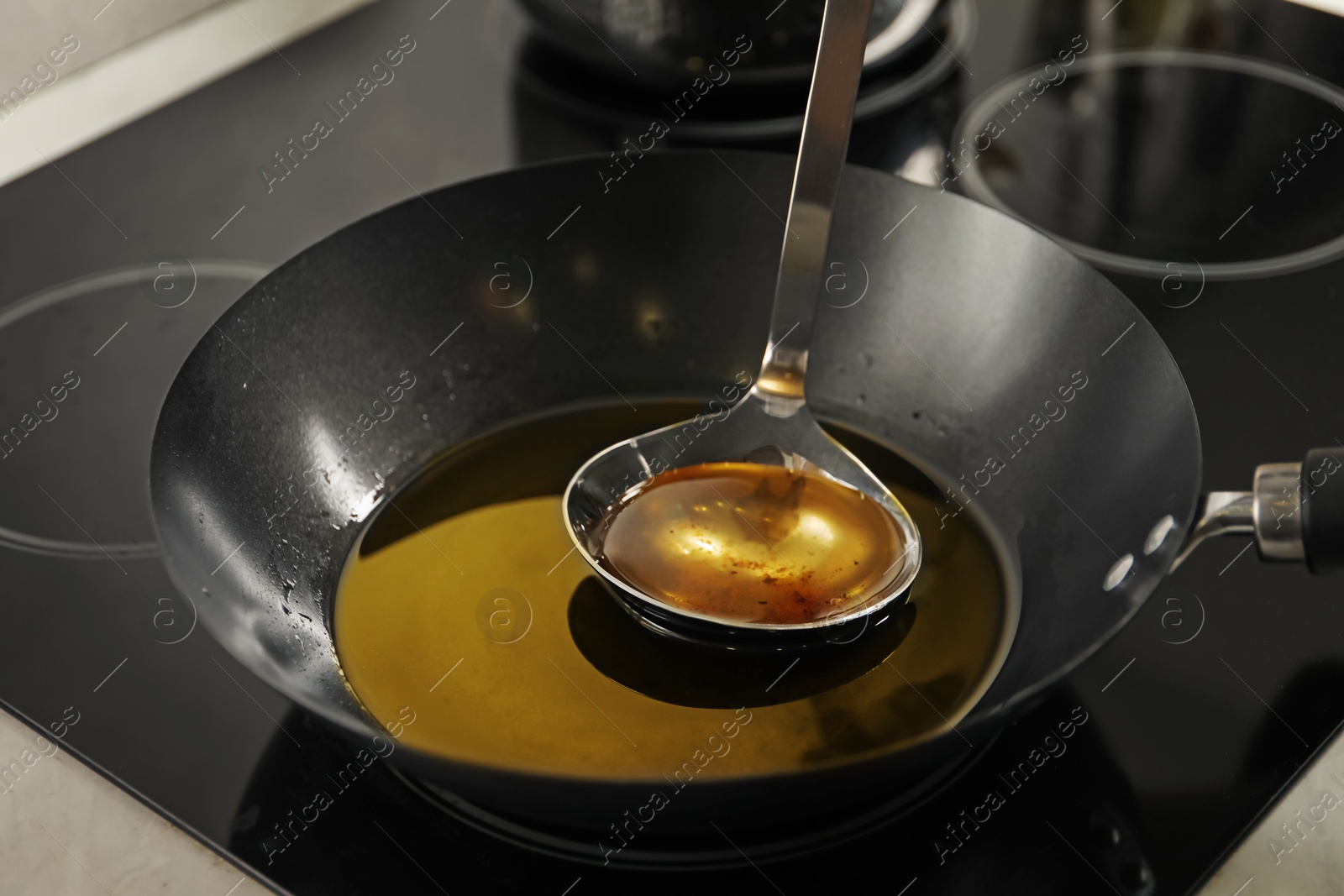 Photo of Used cooking oil and ladle in frying pan on stove, closeup