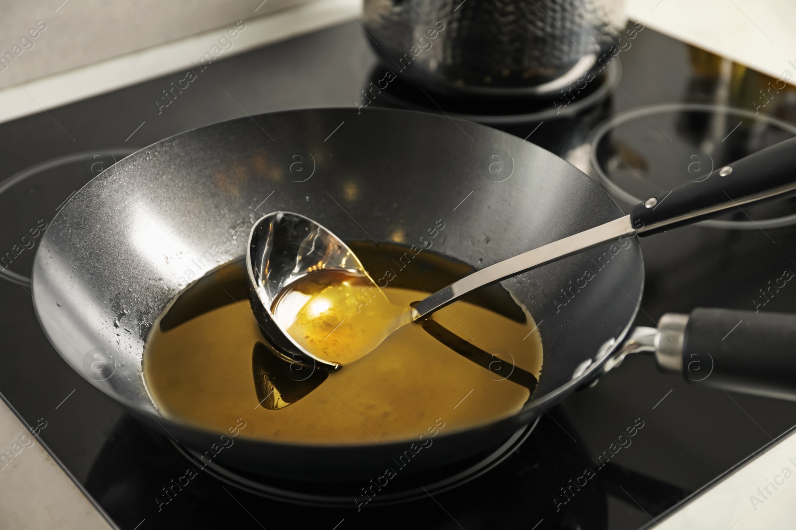 Photo of Used cooking oil and ladle in frying pan on stove, closeup