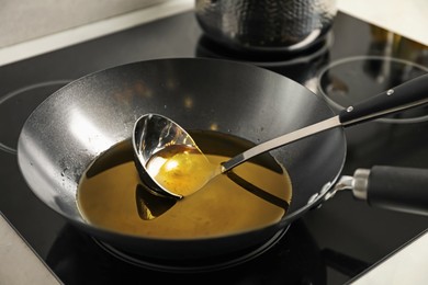 Photo of Used cooking oil and ladle in frying pan on stove, closeup