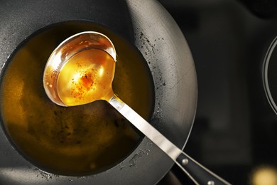 Photo of Used cooking oil and ladle in frying pan on stove, above view