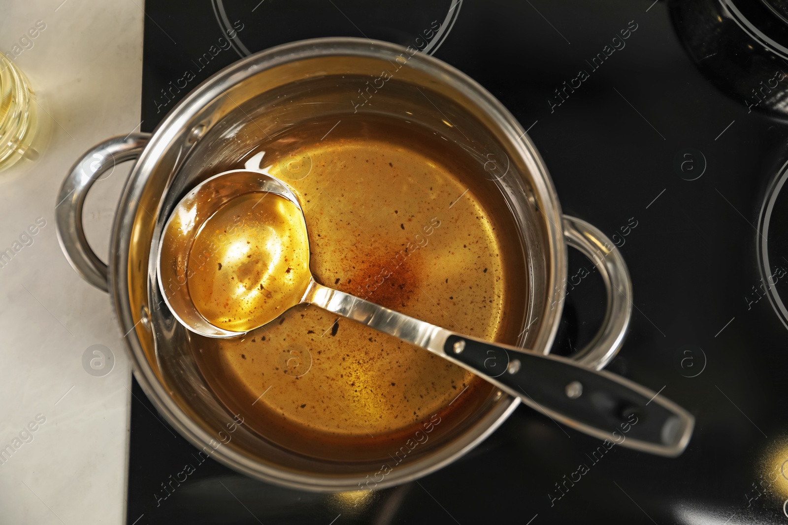 Photo of Used cooking oil and ladle in saucepan on stove, top view