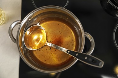 Used cooking oil and ladle in saucepan on stove, top view