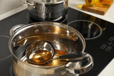 Photo of Used cooking oil and ladle in saucepan on stove