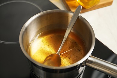 Photo of Used cooking oil and spoon in saute pan on stove, closeup