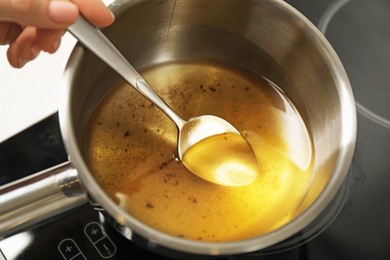 Photo of Woman with saute pan of used cooking oil at stove, closeup